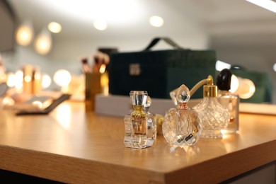 Photo of Beautiful perfume bottles on wooden table in makeup room, space for text