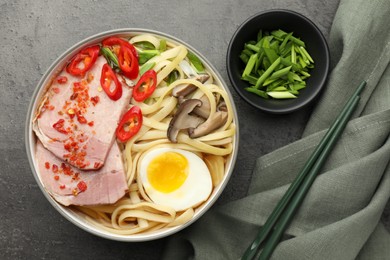 Delicious ramen in bowl served on grey textured table, flat lay. Noodle soup