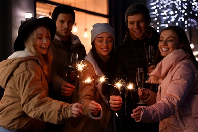 Group of happy friends with sparklers and champagne at winter fair