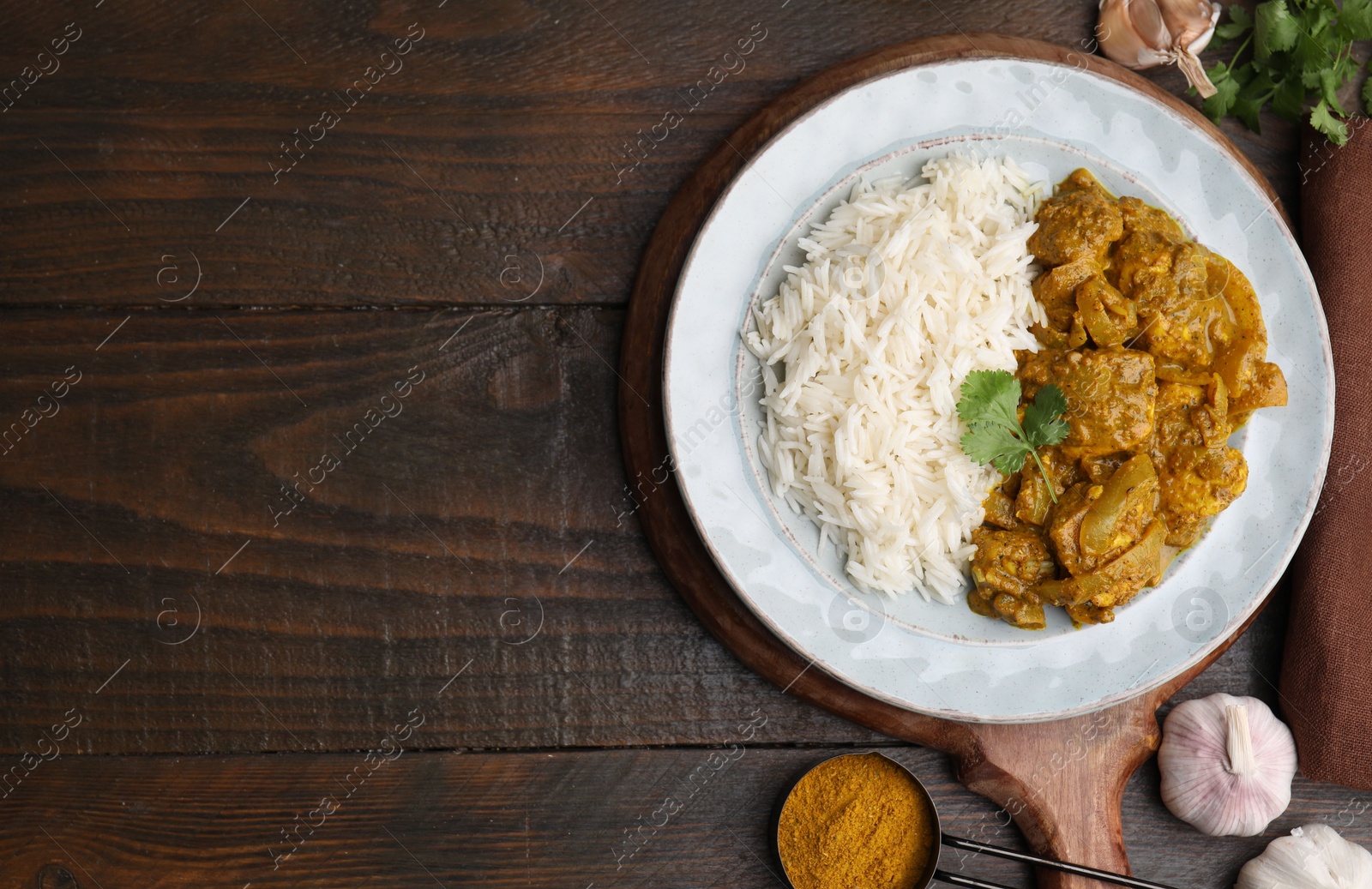 Photo of Delicious chicken curry with rice and ingredients on wooden table, flat lay. Space for text