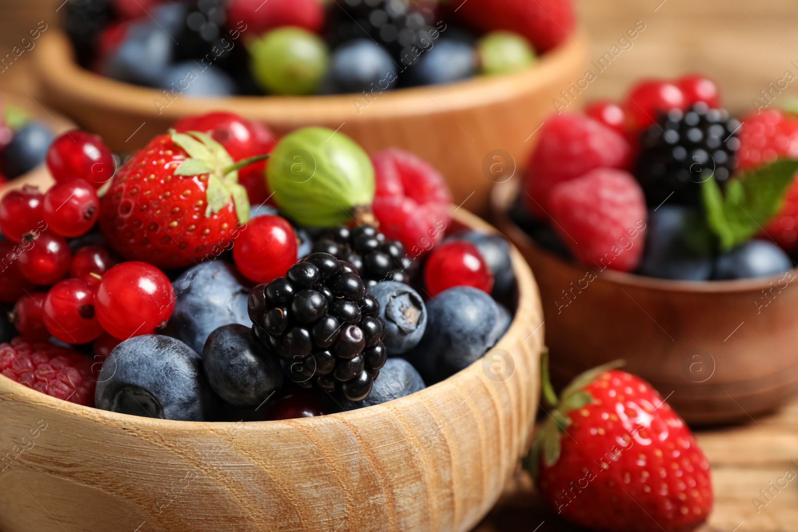 Photo of Mix of ripe berries in bowls, closeup