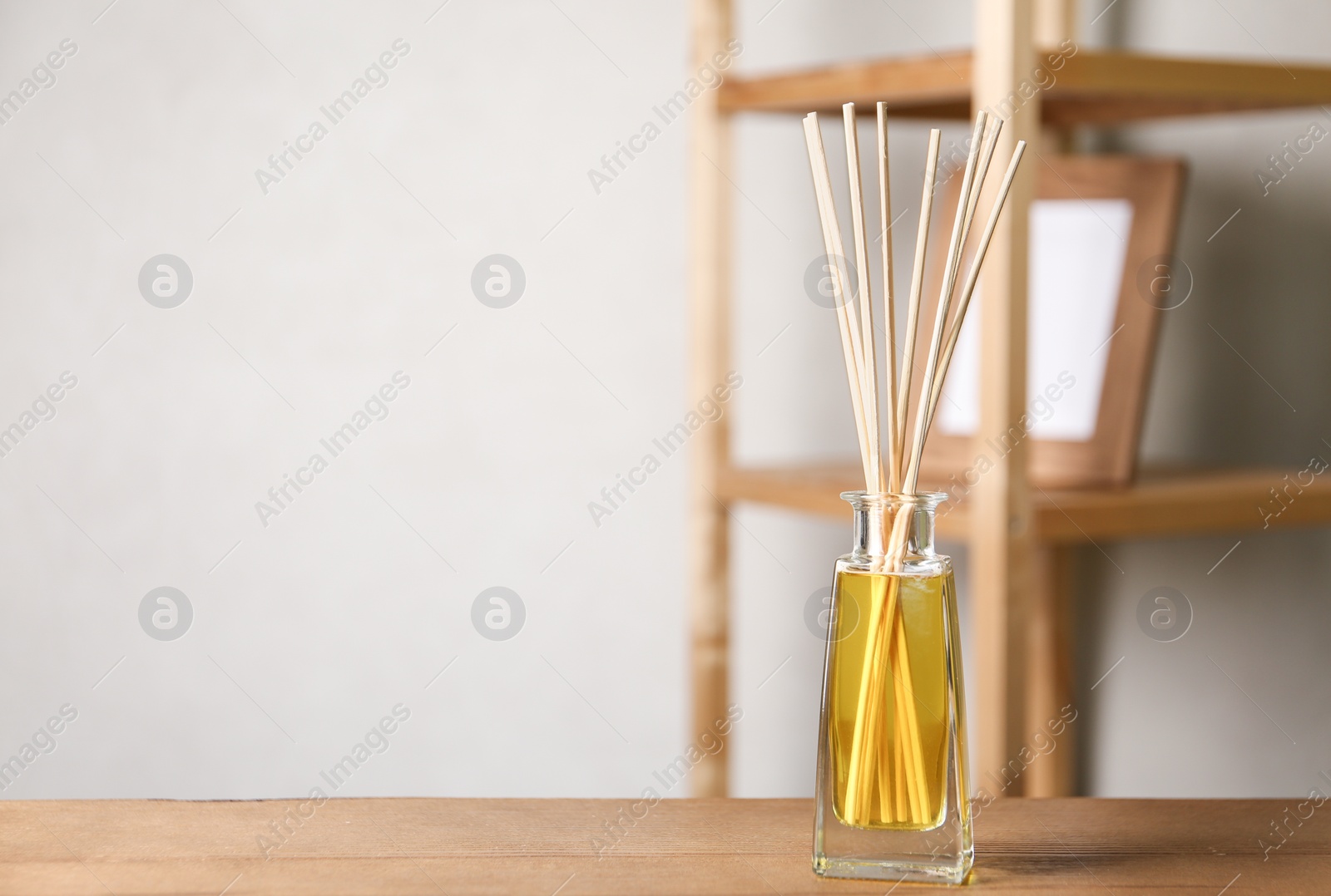 Photo of Reed air freshener on wooden table indoors, space for text