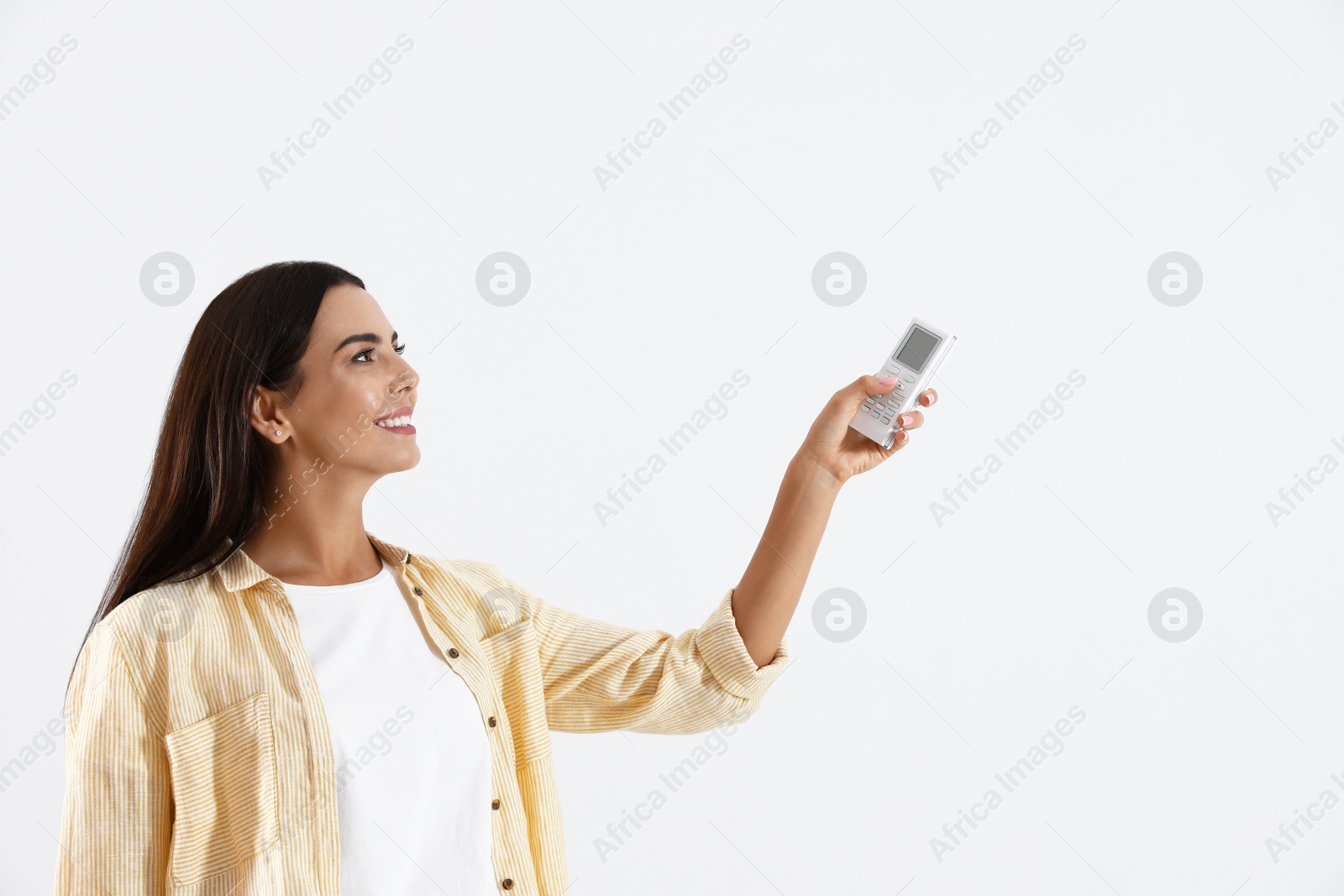 Photo of Young woman turning on air conditioner against white background