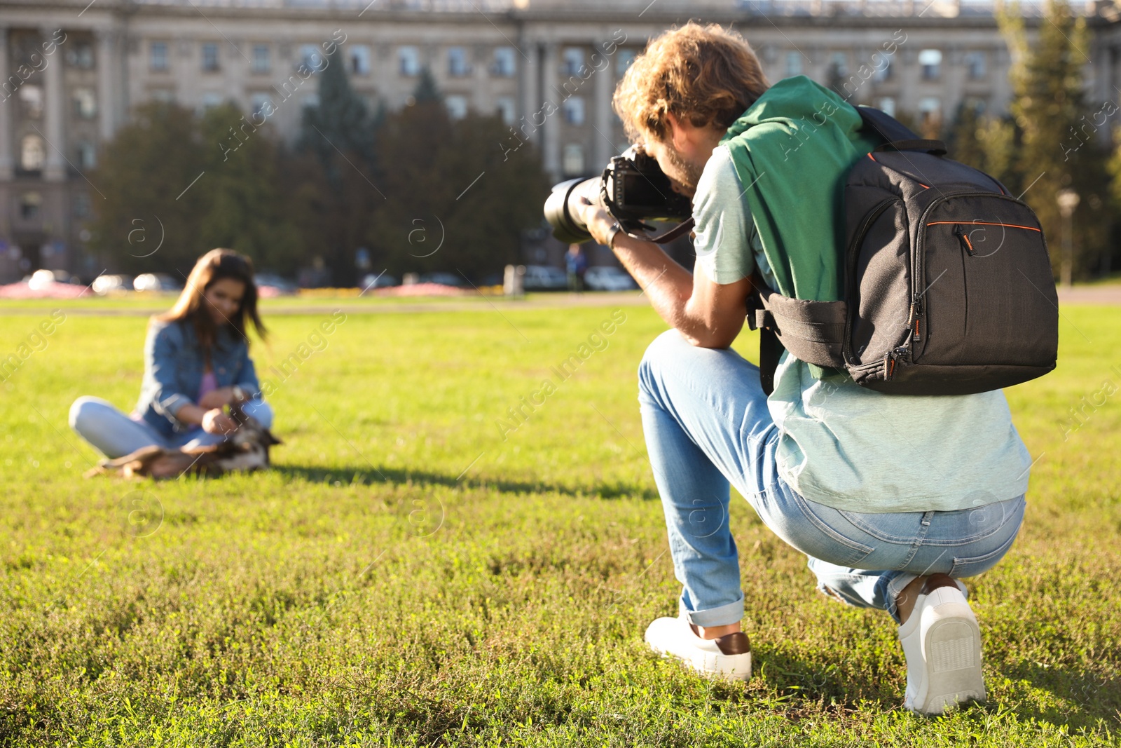 Photo of Male photographer taking photo of young woman with professional camera on grass outdoors