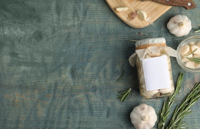 Photo of Flat lay composition with jar of pickled garlic on blue wooden table. Space for text
