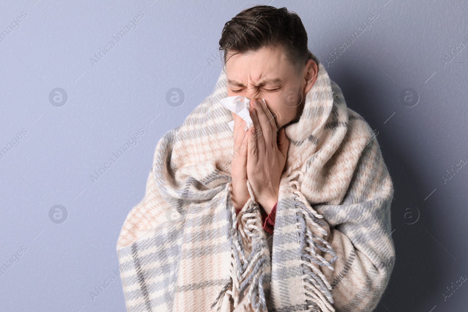 Photo of Man wrapped in blanket suffering from cold on color background