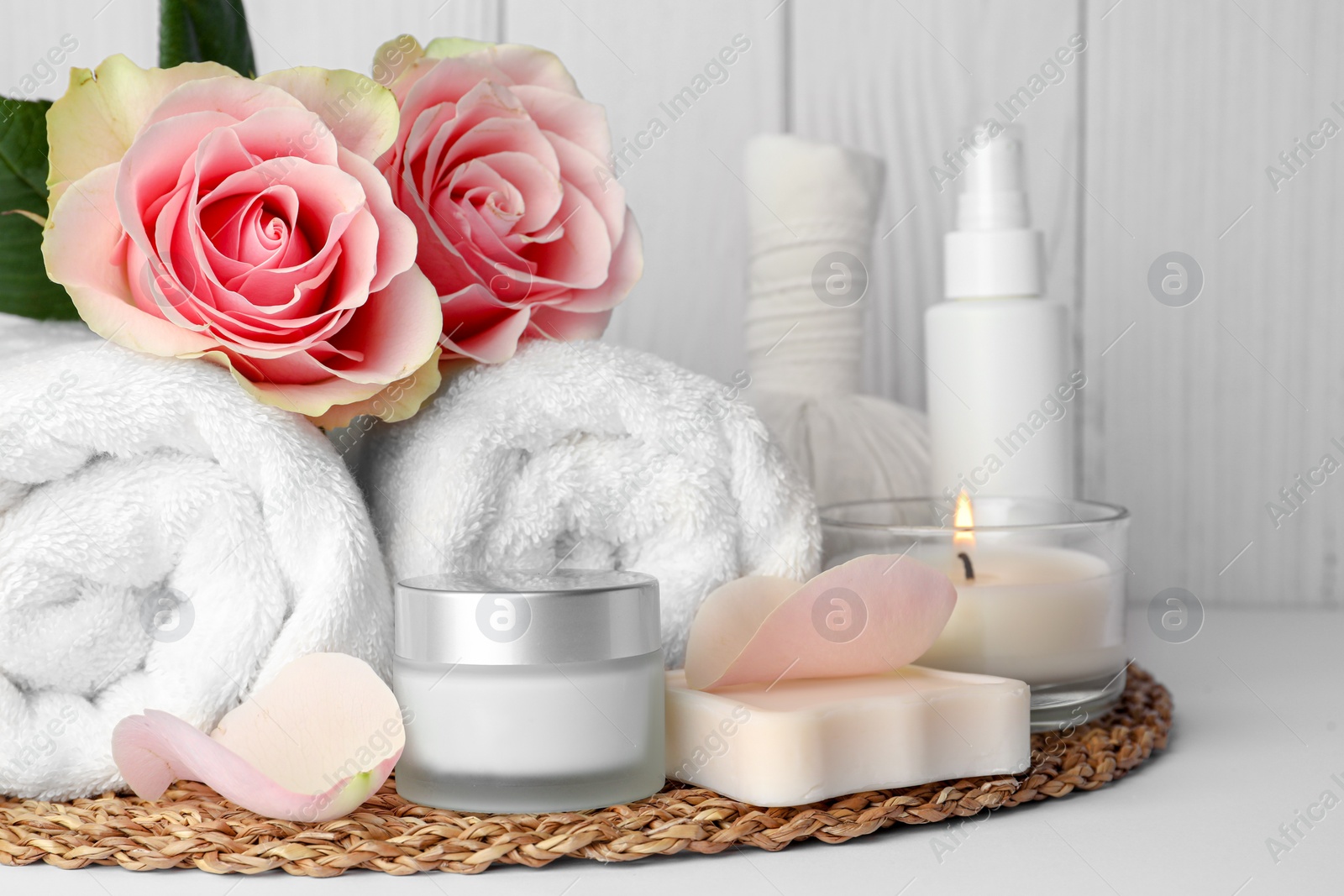 Photo of Composition with different spa products, roses and candle on white table against wooden background