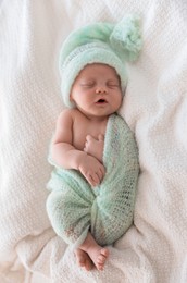 Cute newborn baby in warm hat sleeping on white plaid