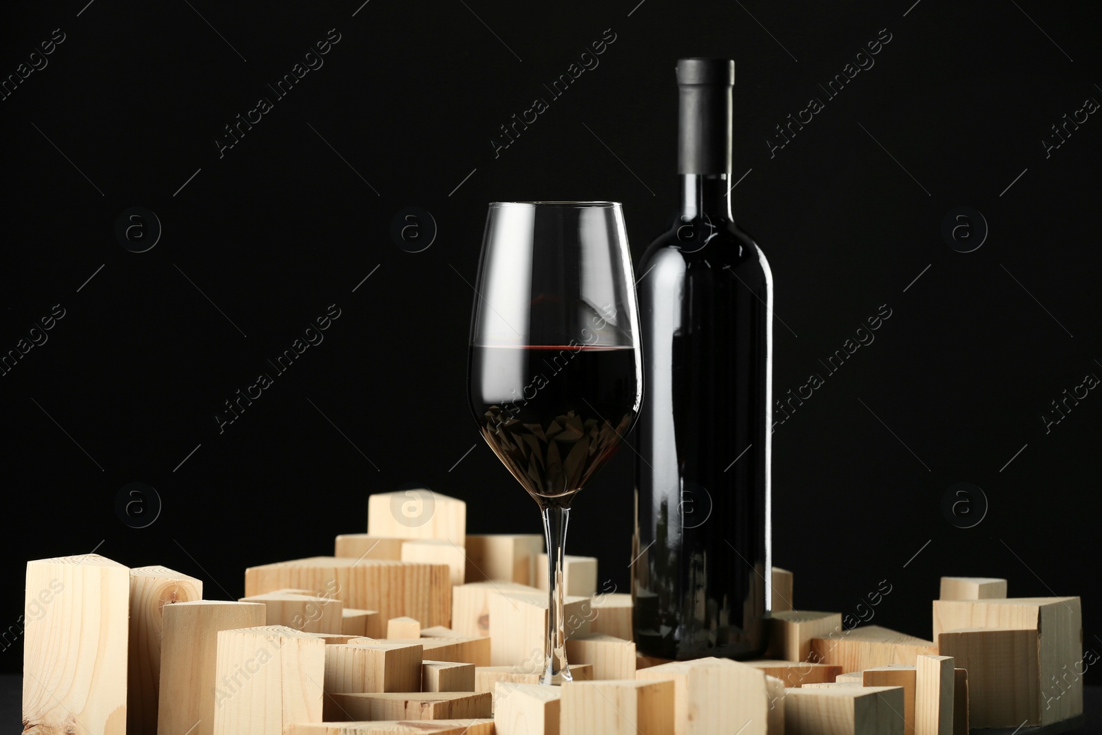 Photo of Stylish presentation of red wine in bottle and wineglass on black background