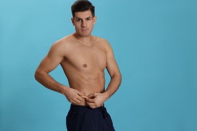 Photo of Fit man with marks on body against light blue background, space for text. Weight loss surgery
