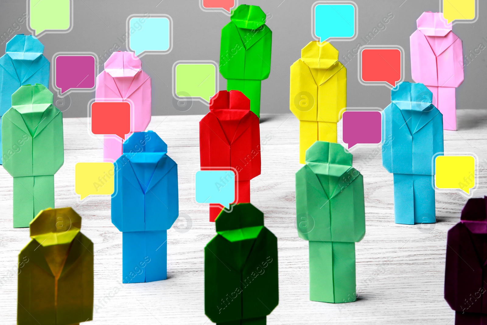 Image of Productive dialogue, meaningful conversation, considerable discussion. Speech bubbles over colorful paper figures on white wooden table