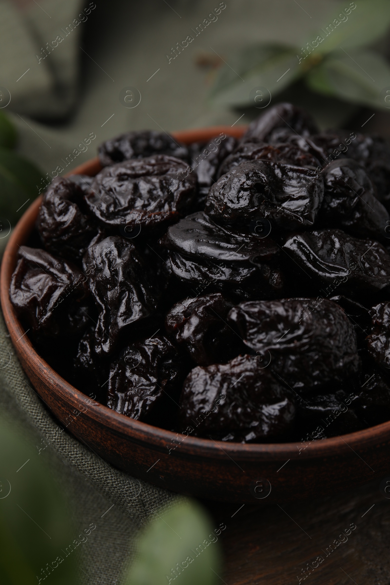 Photo of Sweet dried prunes in bowl on table, closeup