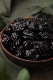 Sweet dried prunes in bowl on table, closeup