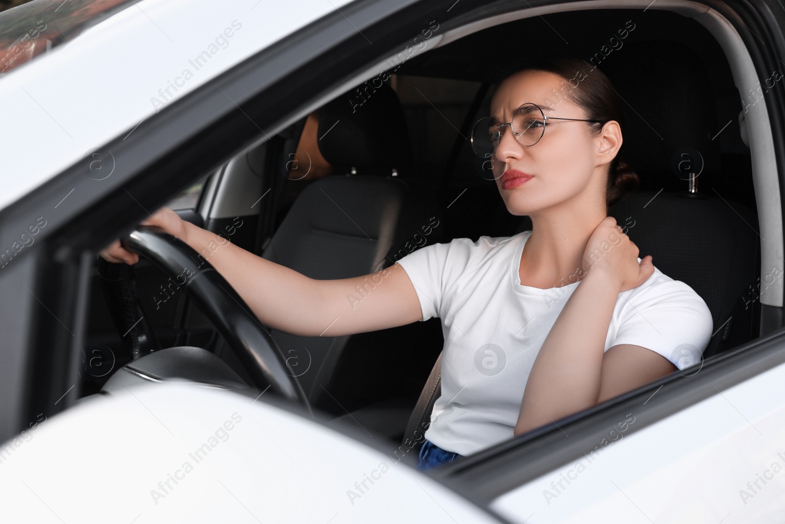 Photo of Young woman suffering from neck pain in her car