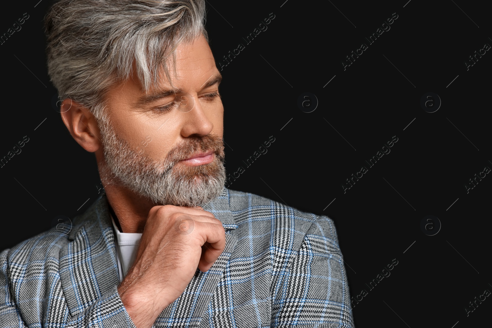 Photo of Portrait of confident man with beautiful hairstyle on black background. Space for text