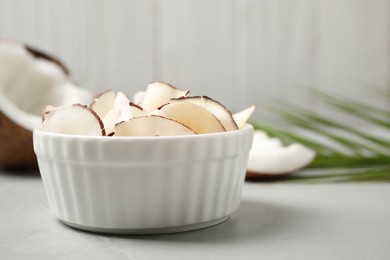 Photo of Tasty coconut chips on grey table against wooden background