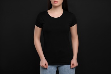 Photo of Woman wearing black t-shirt on dark background, closeup