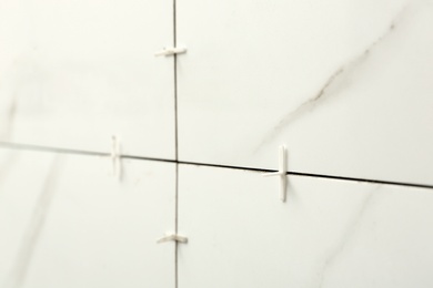 Closeup view of ceramic tiles with plastic crosses in joints on wall. Building and renovation works