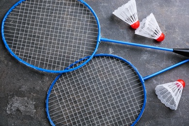 Photo of Rackets and shuttlecocks on black table, flat lay. Badminton equipment