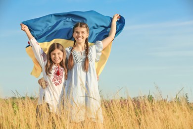 Photo of Happy girls with national flag of Ukraine in field. Space for text