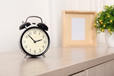 Alarm clock on table in living room, space for text. Time of day