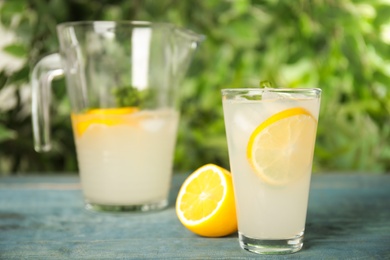 Photo of Cool freshly made lemonade on blue wooden table