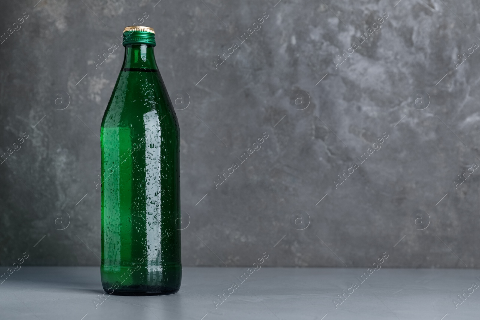 Photo of Glass bottle with water on table against grey background, space for text