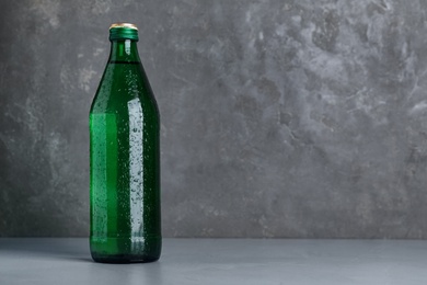 Photo of Glass bottle with water on table against grey background, space for text