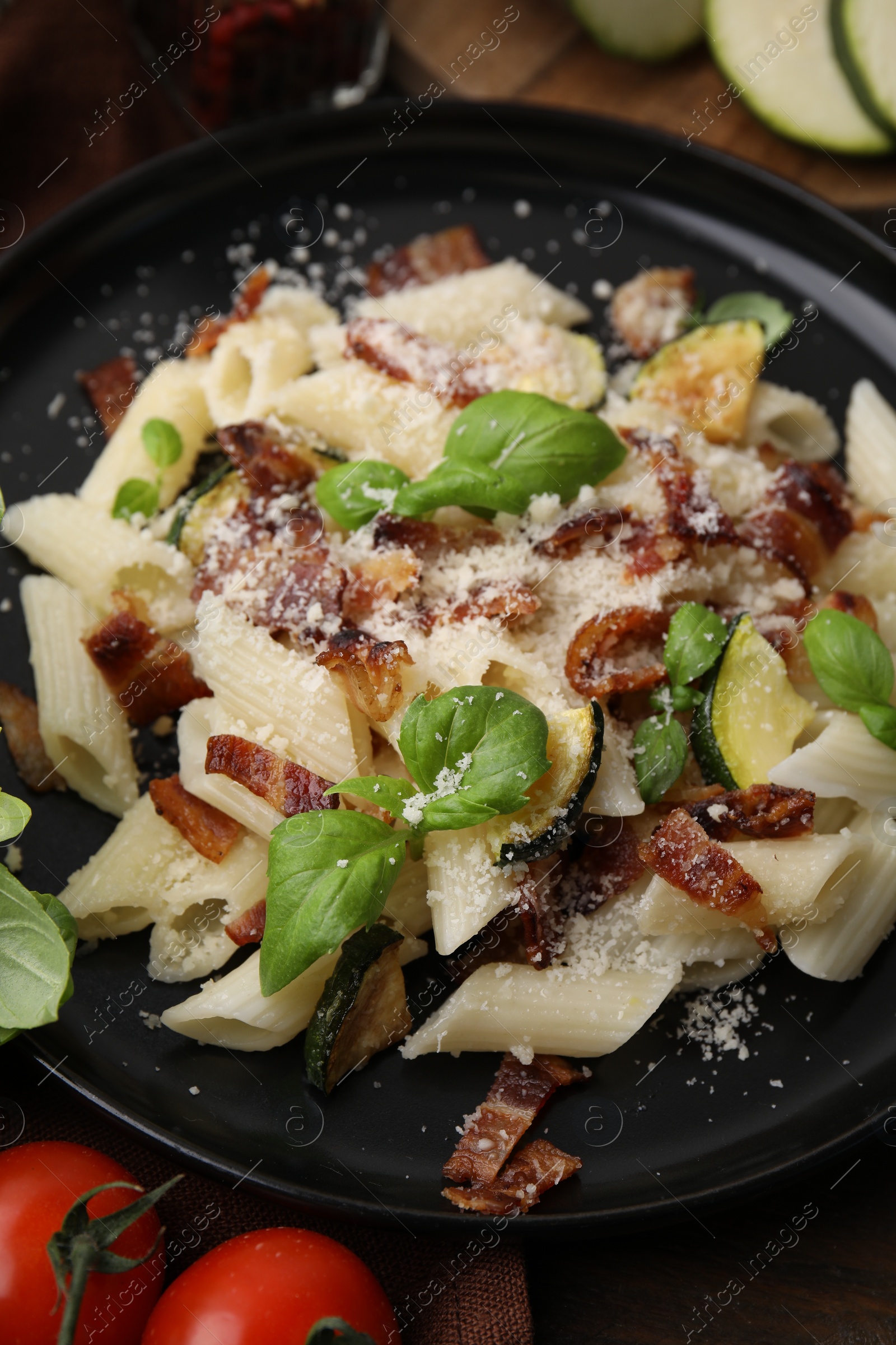 Photo of Tasty pasta with bacon and basil on wooden table, closeup