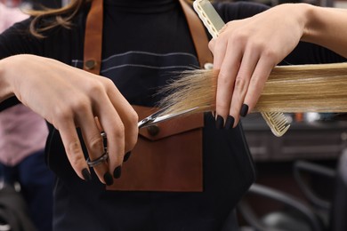 Photo of Professional hairdresser cutting woman's hair in salon, closeup