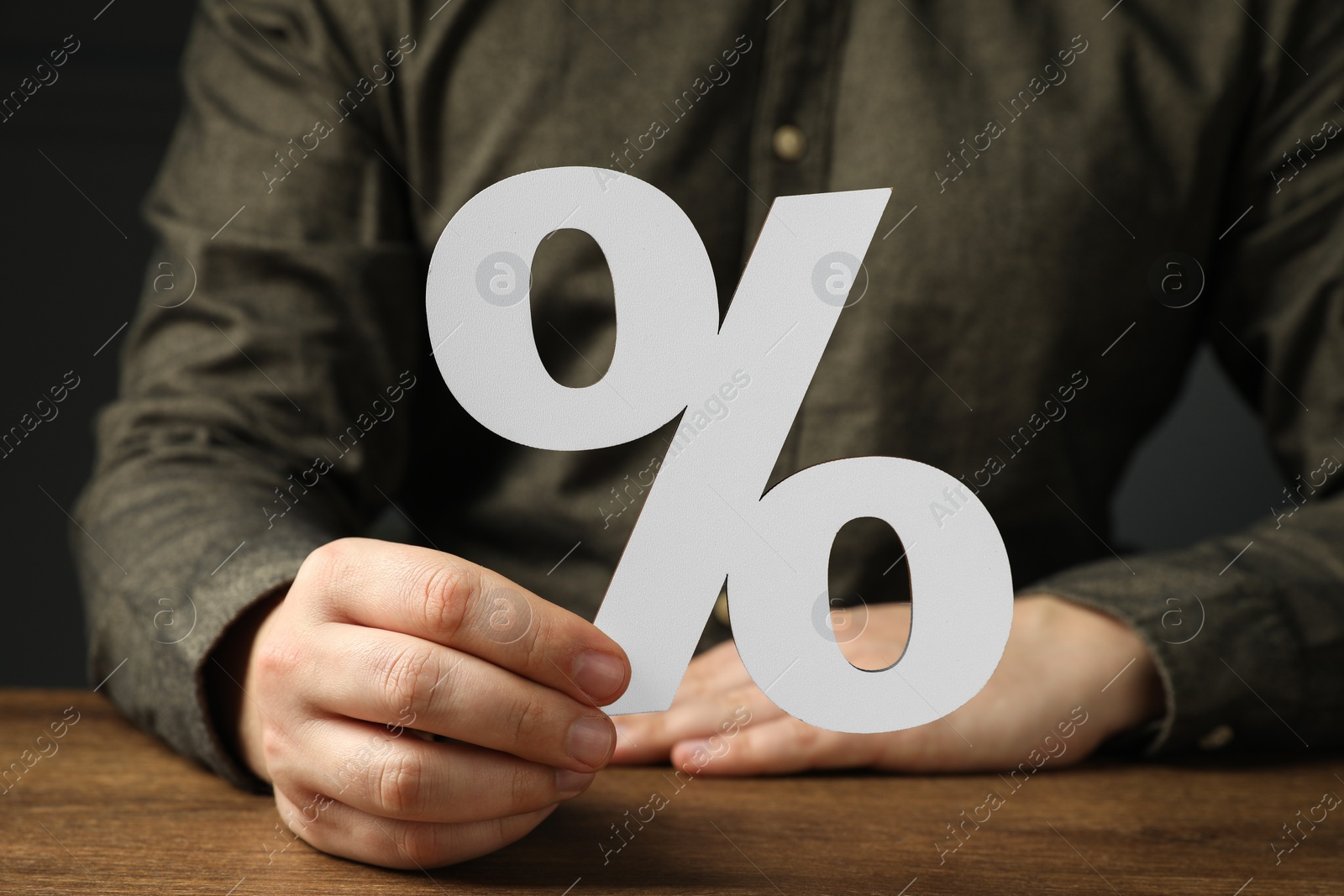 Photo of Man holding percent sign at wooden table, closeup