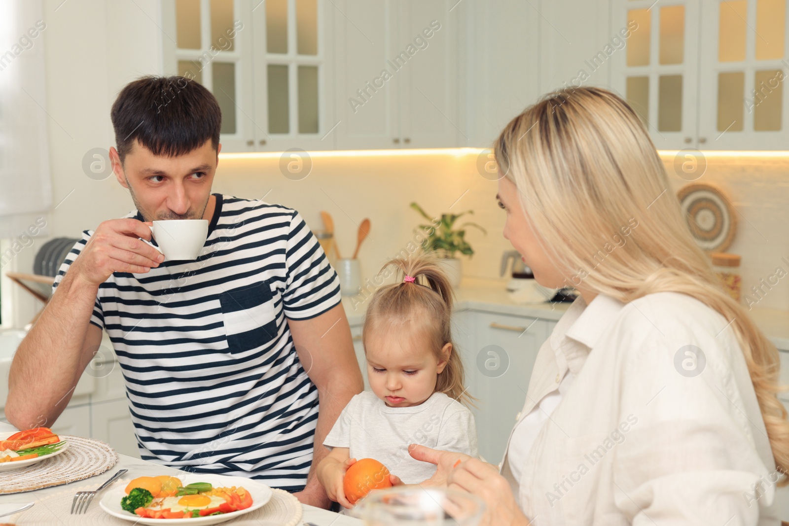 Photo of Happy family having breakfast together at table in kitchen