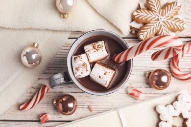 Photo of Flat lay composition with cup of tasty cocoa and Christmas candy canes on white wooden table, flat lay