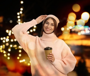 Happy beautiful woman with paper cup of mulled wine at Christmas fair