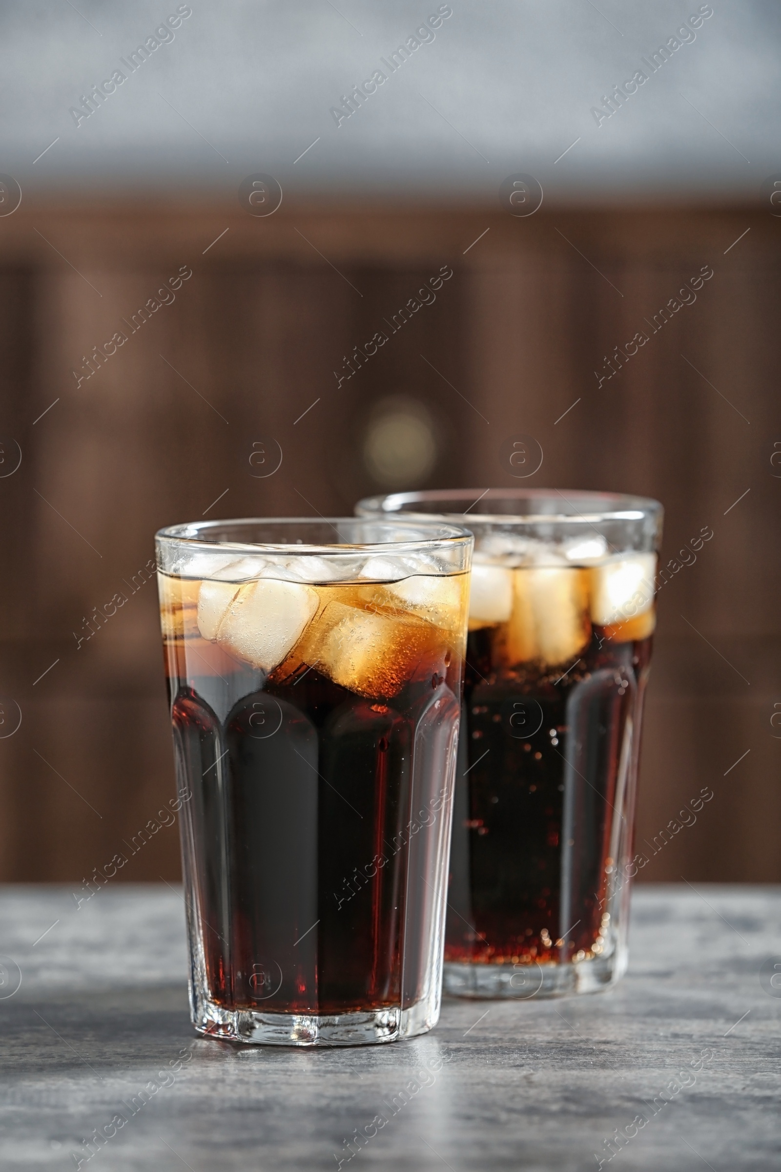 Photo of Glasses of cold cola on table against blurred background. Space for text
