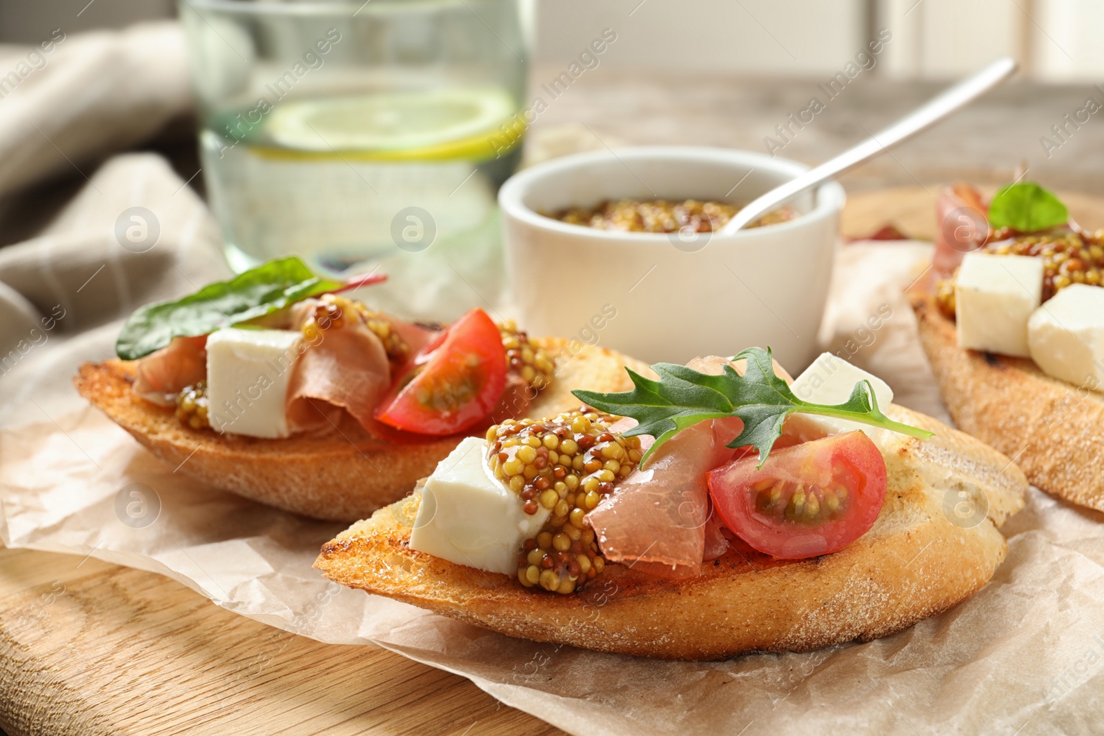 Photo of Delicious bruschettas with prosciutto and cheese served on board