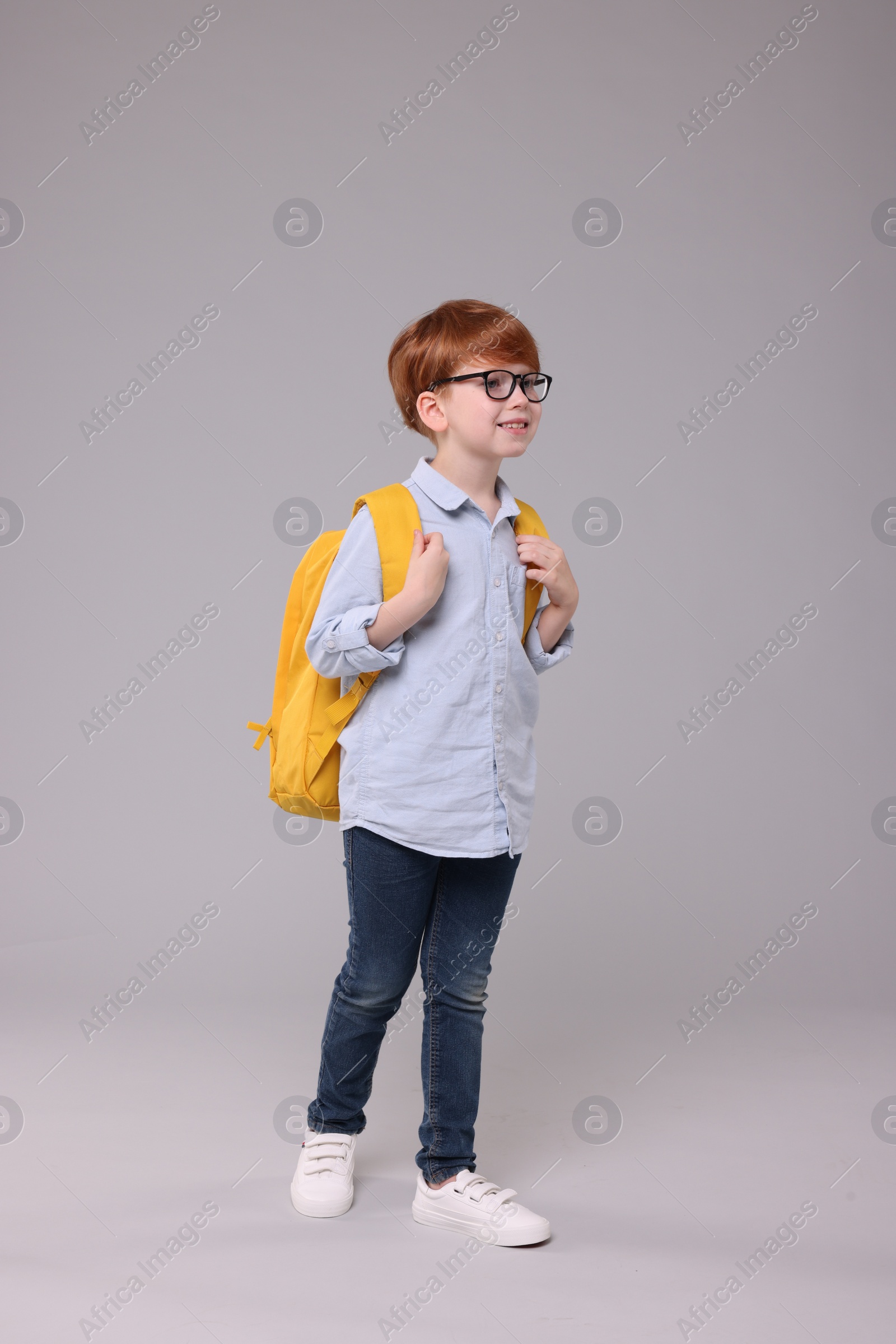 Photo of Happy schoolboy with backpack on grey background