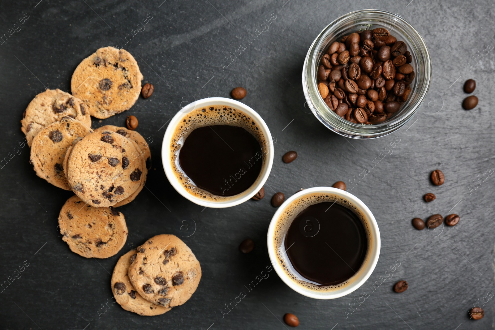 Photo of Flat lay composition with aromatic hot coffee in paper cups and cookies on dark background