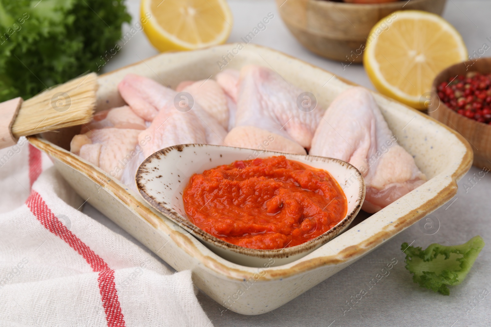 Photo of Fresh marinade, raw chicken and other products on light table, closeup