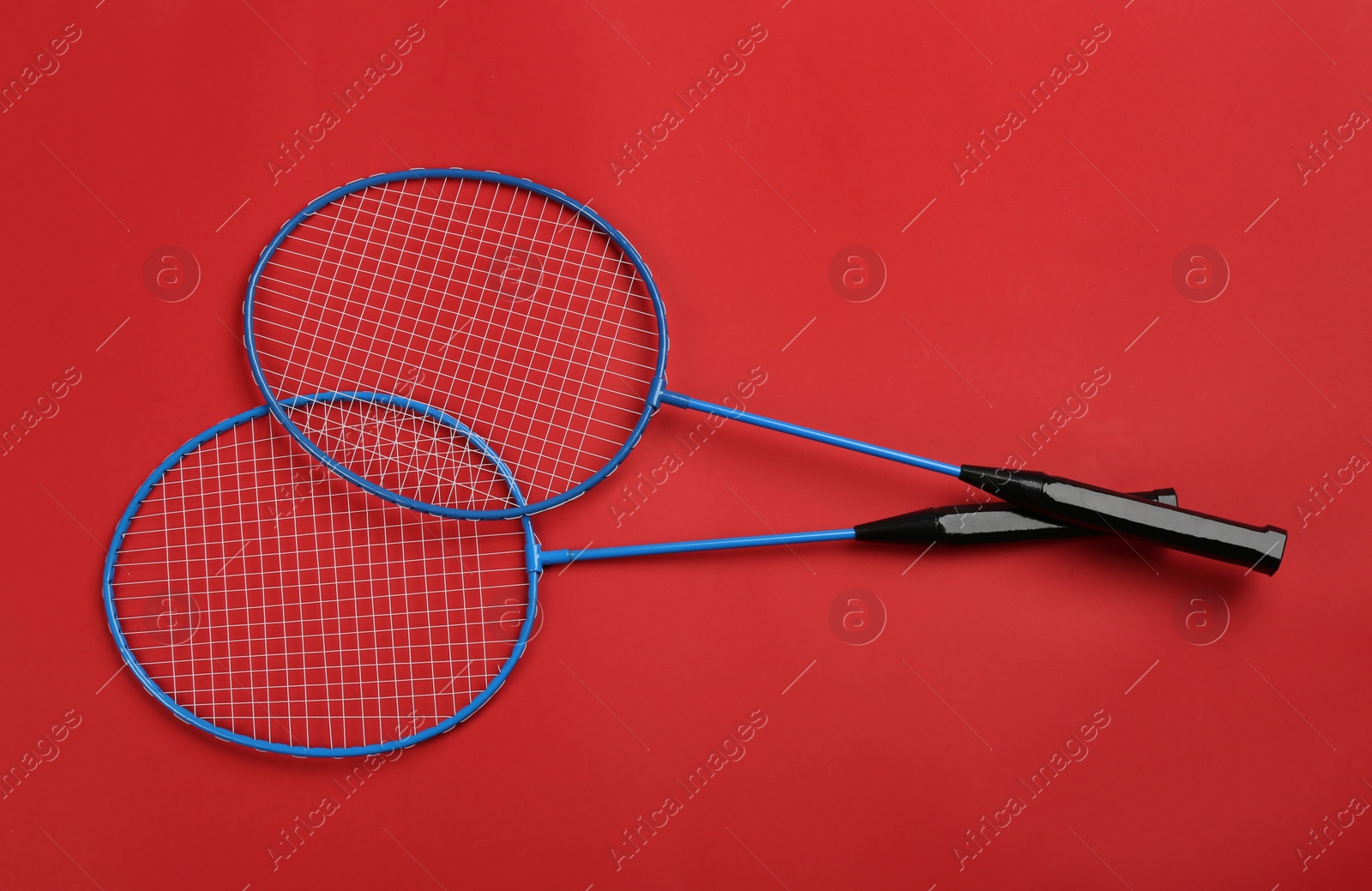 Photo of Rackets on red background, flat lay. Badminton equipment