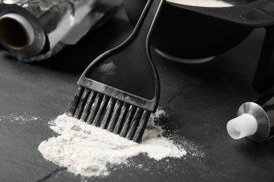 Photo of Brush and hair dye on black stone table, closeup