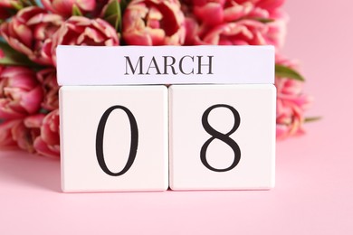 Photo of International Women's day - 8th of March. Block calendar and bouquet of beautiful tulips on pink background, closeup