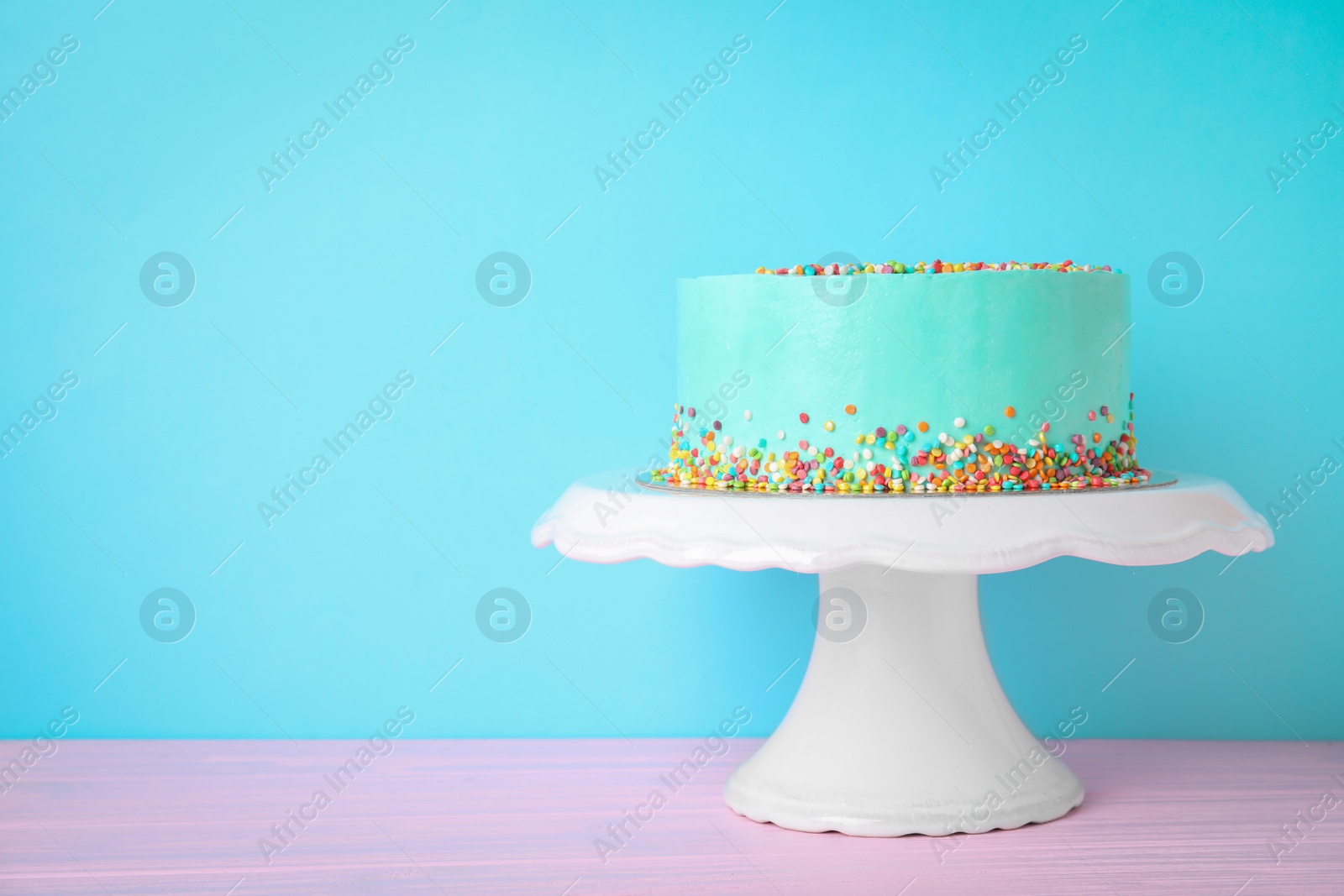 Photo of Fresh delicious birthday cake on stand against color background. Space for text