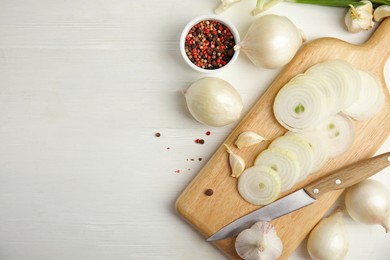 Photo of Garlic, cut onion and bowl with peppers mix on white wooden table, flat lay. Space for text