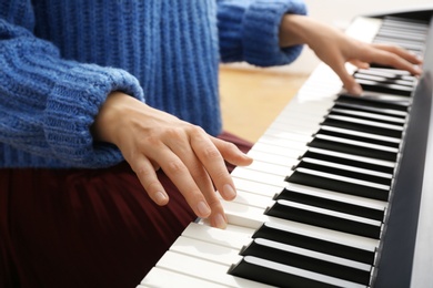 Young woman playing piano at home, closeup