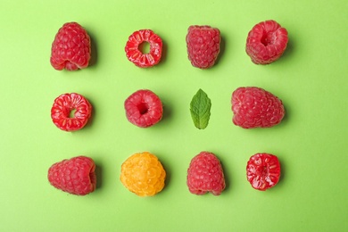 Flat lay composition with delicious ripe raspberries on green background