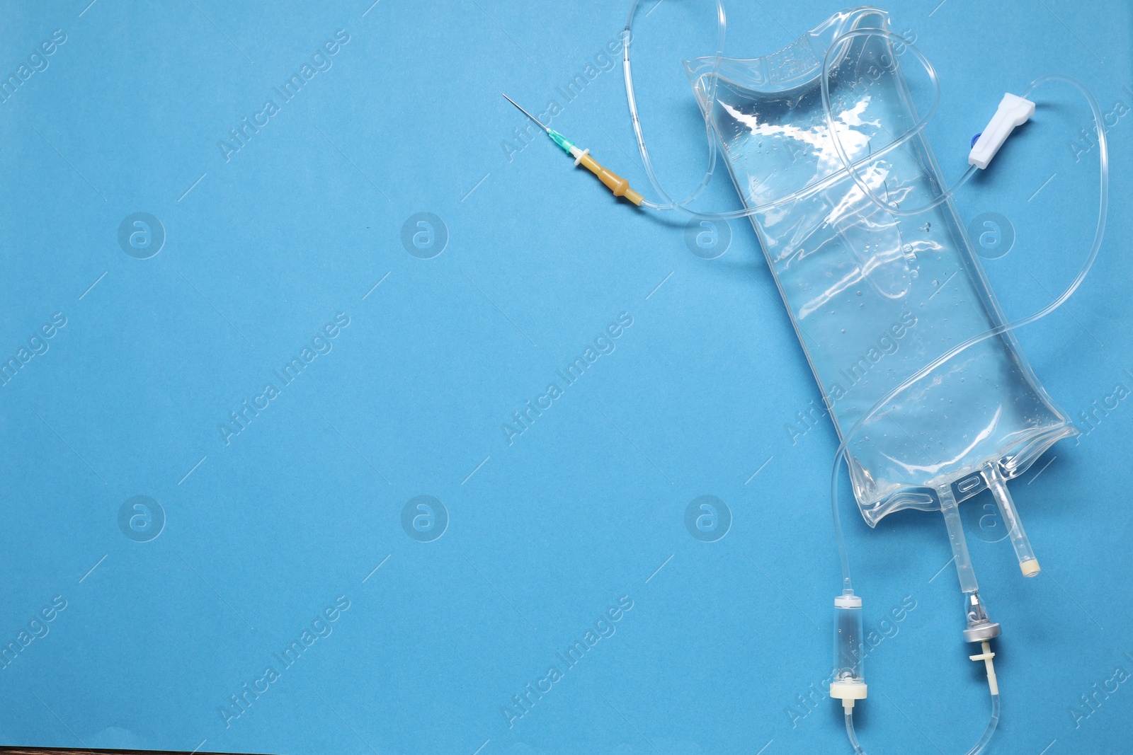 Photo of IV infusion set on light blue background, top view. Space for text