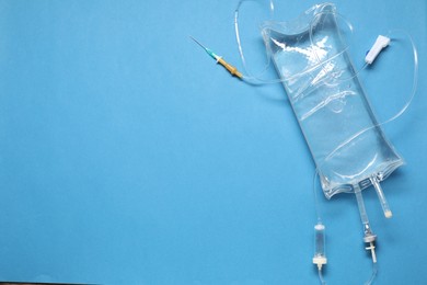 Photo of IV infusion set on light blue background, top view. Space for text