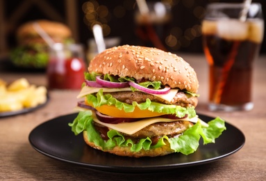 Photo of Plate with delicious hamburger on wooden table