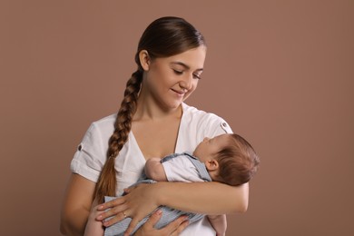 Photo of Mother holding her cute newborn baby on brown background